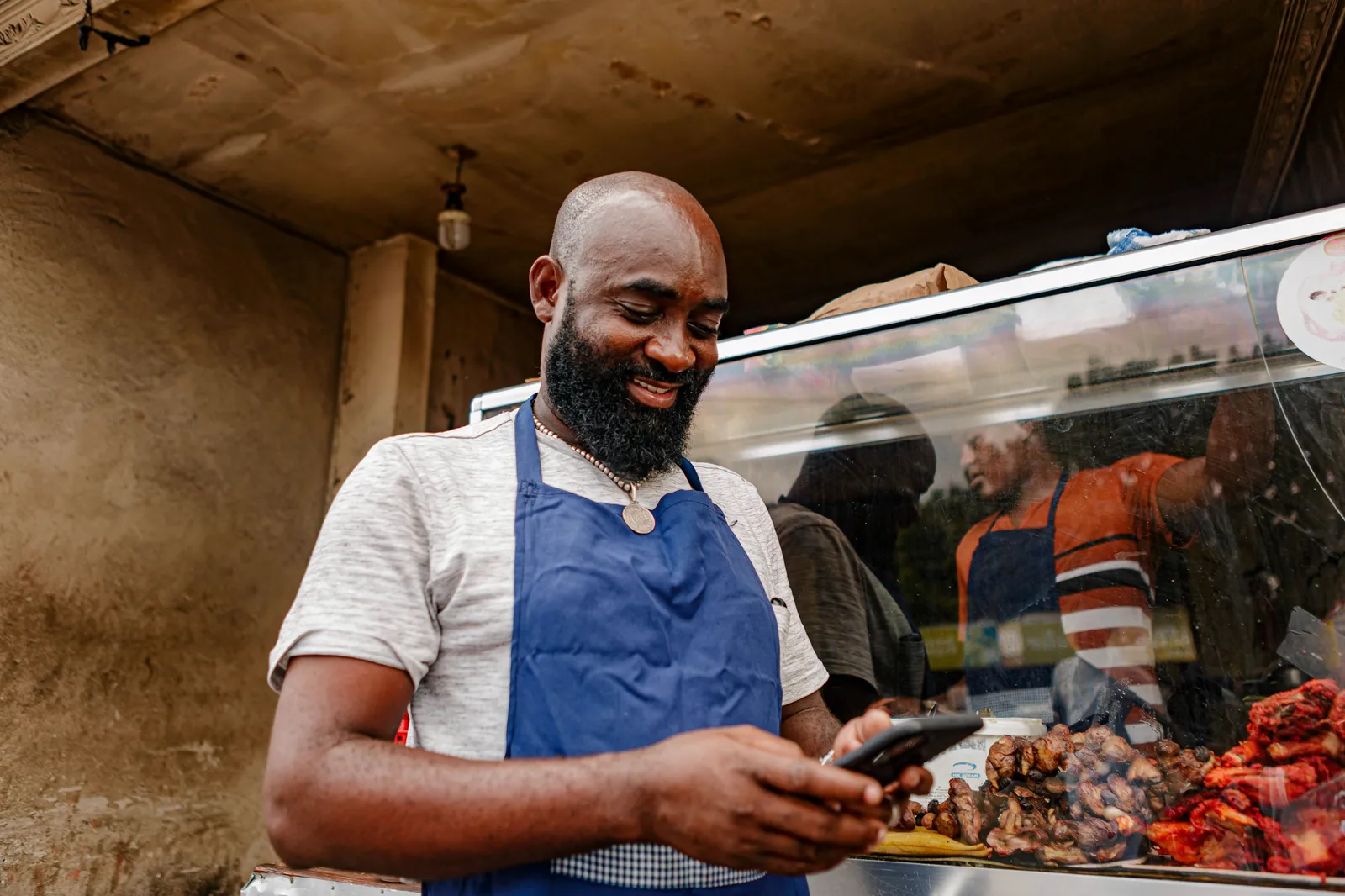 A trader smiling at his phone at his shop counter